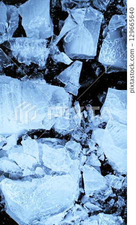 Broken Ice. Crushed Textured Ice with Cracks on a Black Background, Close-up. Abstract Background with Crushed Ice Pieces. Vertical Aspect Ratio. Broken Ice. Crushed Textured Ice with Cracks on a Black Background, Close-up. Abstract Background with Crushed Ice Pieces. Vertical Aspect Ratio. 129665640