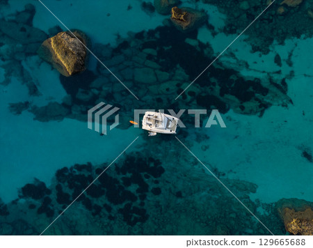 Aerial view of beautiful bay with turquoise water and catamaran boat anchoring. Travel photo, Mallorca, Spain. 129665688