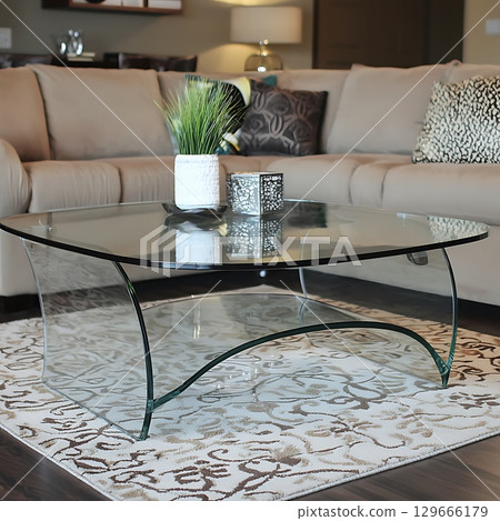 A glass coffee table with a vase of green plants on top of it 129666179