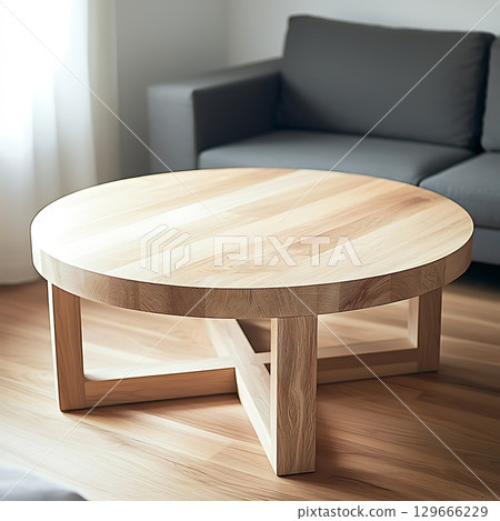 A wooden coffee table with a cross design sits in front of a gray couch 129666229