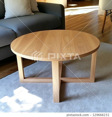 A wooden coffee table with a circular top and a cross shape in the middle 129666231
