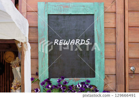 Recognition of successes. Promotion Concept. REWARDS word written on Charming wooden wall with a turquoise-framed chalkboard 129666491