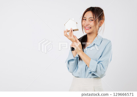 Smiling Asian woman model holds a home miniature, showcasing a finance loan promotion, real estate concepts for a residential house concept, buy or rent a house, headshot isolated white background Smiling Asian woman model holds a home miniature, showcasing a finance loan promotion, real estate concepts for a residential house concept, buy or rent a house, headshot isolated white background 129666571