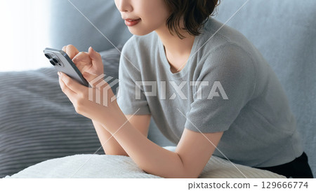 坐長沙發和使用智能手機的婦女 坐長沙發和使用智能手機的婦女 129666774