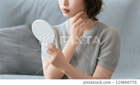 一個女人在鏡子裡檢查她的皮膚 129666778