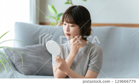 一個女人在鏡子裡檢查她的皮膚 129666779