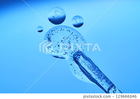 Beautiful serum texture with a pipette on a blue background. Beautiful serum texture with a pipette on a blue background. 129666846