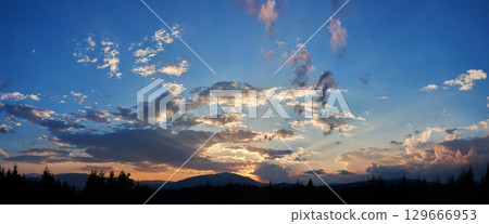 Serene evening sky with hues of blue and soft pink clouds as sun sets. Horizon glows gently, casting light over silhouetted pine trees and rolling hills, creating peaceful and expansive landscape. Serene evening sky with hues of blue and soft pink clouds as sun sets. Horizon glows gently, casting light over silhouetted pine trees and rolling hills, creating peaceful and expansive landscape. 129666953