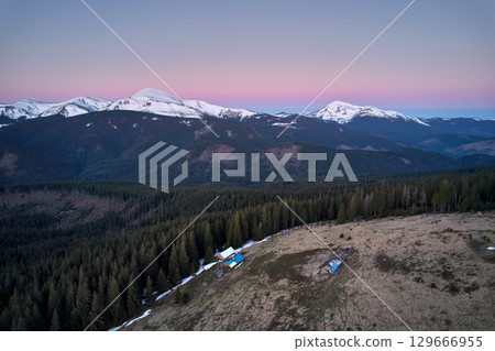 Beautiful panorama of alpine village with spruce trees and snow-capped mountains under evening sky Beautiful panorama of alpine village with spruce trees and snow-capped mountains under evening sky 129666955