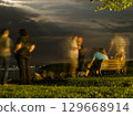 Blurred Figures by the Lake at Night 129668914