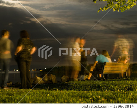 Blurred Figures by the Lake at Night Blurred Figures by the Lake at Night 129668914
