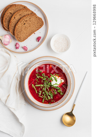Traditional Ukrainian borscht with sour cream, garlic and rye bread on white table. Top view 129668998