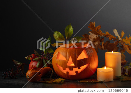 Halloween pumpkin head jack lantern with dried-up leaves. Halloween pumpkin head jack lantern with dried-up leaves. 129669046