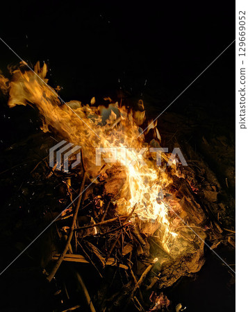 A fire is burning in a pile of wood. A fire is burning in a pile of wood. 129669052