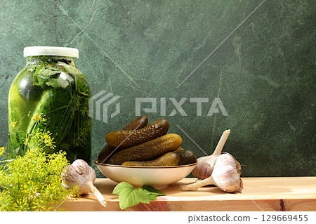 Fresh pickled cucumbers in a bowl with garlic and dill on a concrete table, village harvest, homemade pickling recipe, cucumbers and ingredients for pickling, home canning concept 129669455