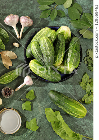 Fresh cucumbers in bowl, spices, garlic and leaves on concrete table, village harvest, homemade pickling recipe, cucumbers and pickling ingredients, home canning concept, healthy and natural food Fresh cucumbers in bowl, spices, garlic and leaves on concrete table, village harvest, homemade pickling recipe, cucumbers and pickling ingredients, home canning concept, healthy and natural food 129669463