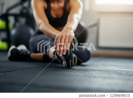 Woman stretching on rubber flooring in a gym, promoting fitness and healthy lifestyle choices 129669653