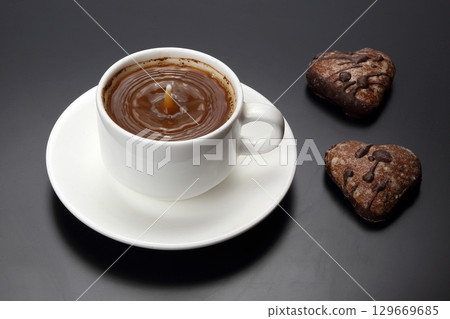 Warm cup of hot chocolate with heart-shaped cookies on black background 129669685