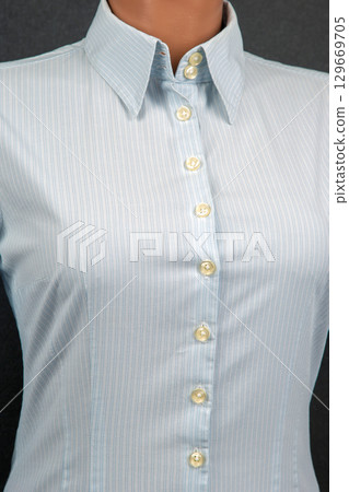 Elegant light blue button-down shirt displayed on a mannequin with subtle pinstripes 129669705