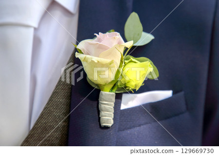 Elegant boutonniere displayed on a suit pocket in a formal setting during a wedding ceremony Elegant boutonniere displayed on a suit pocket in a formal setting during a wedding ceremony 129669730
