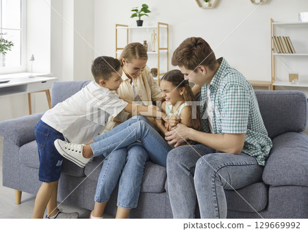 Funny Caucasian woman, man and their son and daughter having fun tickling each other together. 129669992