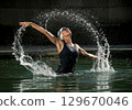 Female swimmer performing dynamic water splash in a pool showcasing athleticism and grace 129670046