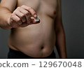 Man holding sugar cube, showcasing harmful effects of sugar on health and body image 129670048