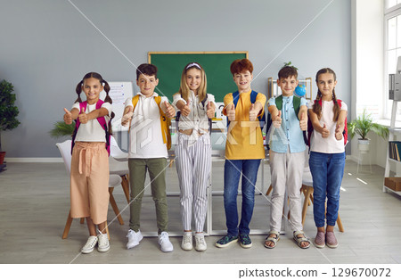 Team of joyful preteen schoolchildren in classroom show thumbs up showing their approval. Team of joyful preteen schoolchildren in classroom show thumbs up showing their approval. 129670072