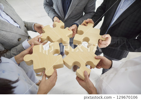 Close-Up Of Business Team Connecting Puzzle Pieces 129670106