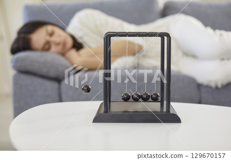 Newton Cradle On Table With Woman Sleeping At Home 129670157