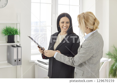 Two women colleagues working in office, discussing business project, collaborate together 129670159