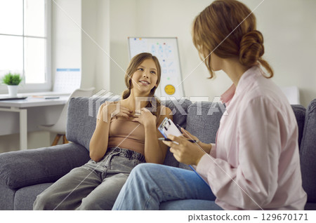 Cheerful teenage girl talks to female psychologist talking about positive emotions she felt. 129670171