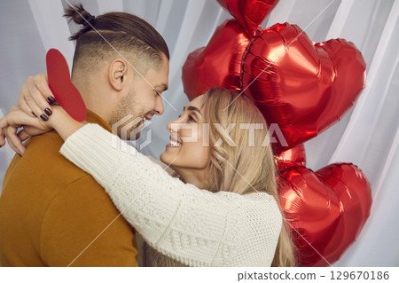 Portrait of young man and woman holding red heart in her hands and hugging. Couple in love. Portrait of young man and woman holding red heart in her hands and hugging. Couple in love. 129670186