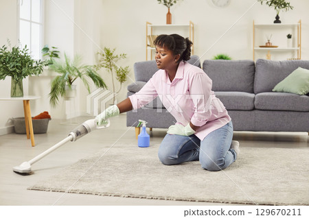 Young African American woman cleaning house using modern wireless vacuum cleaner Young African American woman cleaning house using modern wireless vacuum cleaner 129670211