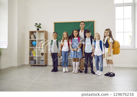 Group portrait of friendly teacher with her young schoolchildren in school classroom. Group portrait of friendly teacher with her young schoolchildren in school classroom. 129670238
