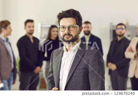 Portrait of a confident boss and business man leader with team of people in background. 129670240