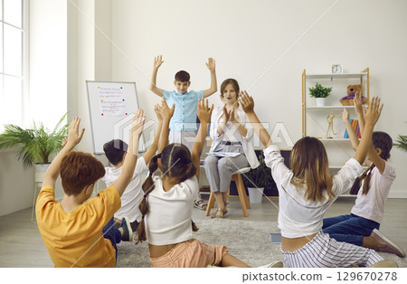 Happy school students with teacher playing games and having fun in the classroom Happy school students with teacher playing games and having fun in the classroom 129670278