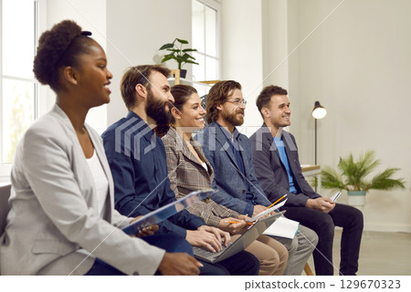 Smiling different people listening to speaker's speech at business training or seminar. Smiling different people listening to speaker's speech at business training or seminar. 129670323