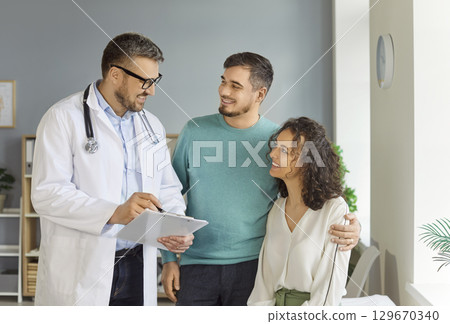 Happy smiling family couple talking about fertility treatment with doctor at clinic 129670340