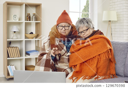 Sick frozen senior couple sitting on sofa and having online video call at home. Sick frozen senior couple sitting on sofa and having online video call at home. 129670398