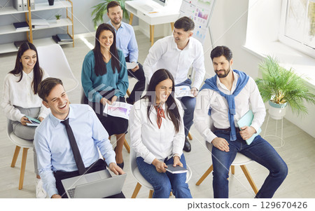 Business people sitting on a meeting in office listening to colleague during a conference. Business people sitting on a meeting in office listening to colleague during a conference. 129670426