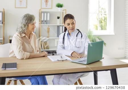Doctor showing examination results on laptop and giving consultation to a senior patient in clinic Doctor showing examination results on laptop and giving consultation to a senior patient in clinic 129670438