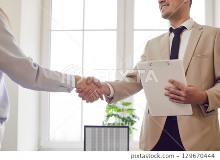 Confident diverse business people shaking hands in office close up, customer giving handshake 129670444