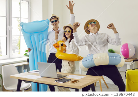 Funny happy company employees standing in office going on summer vacation trip. 129670448