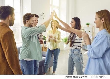 Group of excited happy friends greeting each other giving high five when meet at home. Group of excited happy friends greeting each other giving high five when meet at home. 129670480