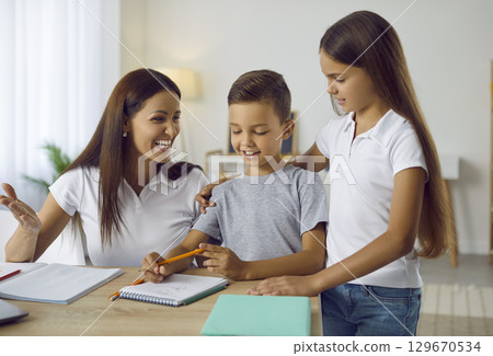 Happy caring mom doing homework with her son and daughter 129670534