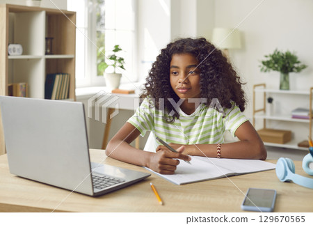 Smiling African American Girl studying with laptop computer Smiling African American Girl studying with laptop computer 129670565