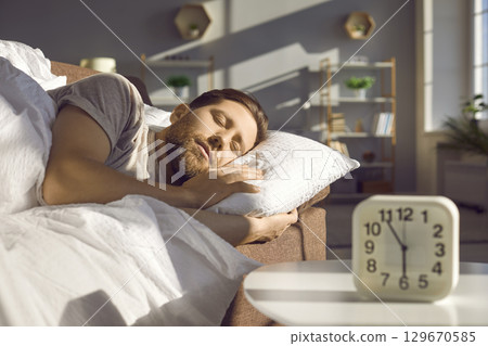 Guy is sleeping sweetly, lying in his cozy bed at home in the living room. 129670585