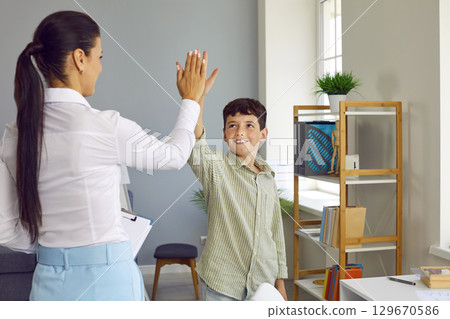 Happy little boy gives a high five to his psychologist after a successful therapy session Happy little boy gives a high five to his psychologist after a successful therapy session 129670586