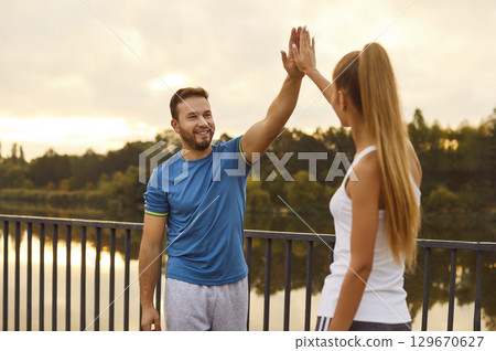 Couple giving high five each other rejoicing the success in sport training outdoors. 129670627